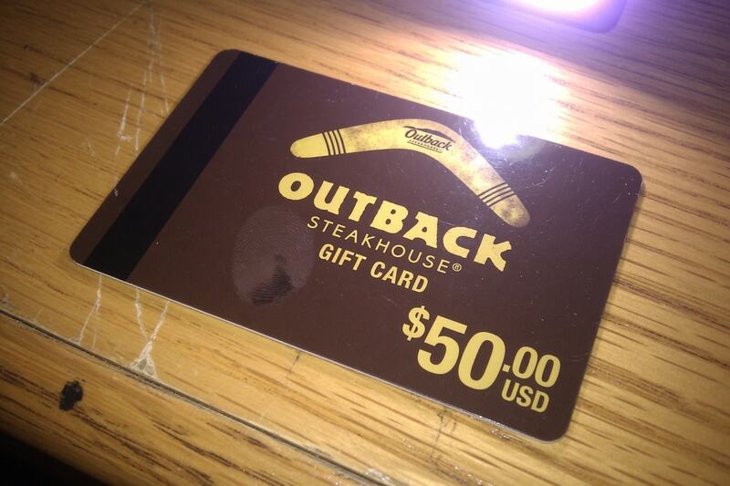 A $50.00 Outback Steakhouse gift card, photographed on a desk.